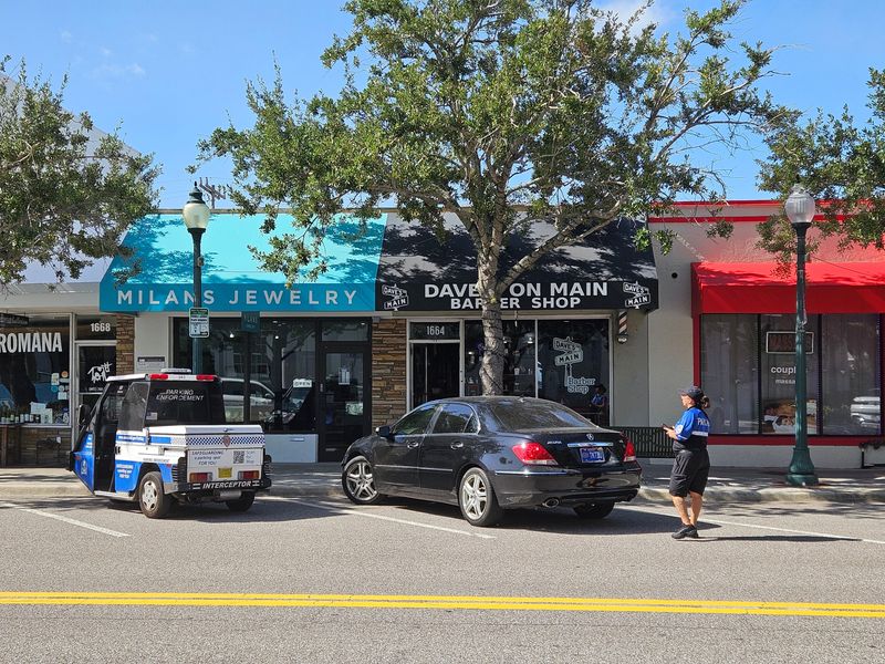 Paid parking signs and parking enforcement vehicles are seen in downtown Sarasota on July 22, 2026. Sarasota business owners have urged city commissioners to reconsider recently expanded paid parking hours, saying the changes are hurting local businesses.