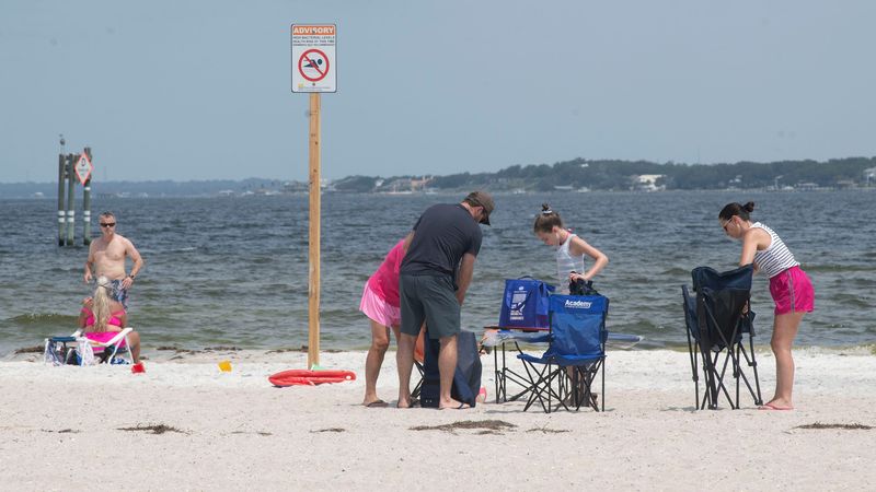 Despite health warning signs, beachgoers sunbath and play in the soundside waters at Pensacola Beach on Monday, July 27, 2026. On July 24, 2026, the Florida Department of Health issued a water quality advisory for several public beaches, including Park West, soundside, Baby Beach and Quietwater Beach.