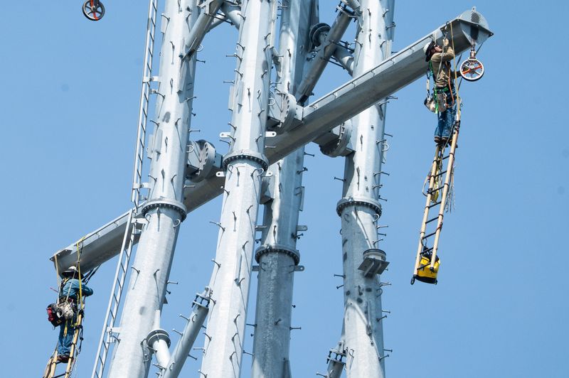 Workers with Gulf Services Contracting Inc. install pulleys and “p” lines on the  JEA Fulton Cut project, over 300 feet in the air on a transmission tower. JEA expects the six new lines will be fully electrified by the end of the year, allowing future demolition of the old transmission towers.[Doug Engle/Florida Times-Union]