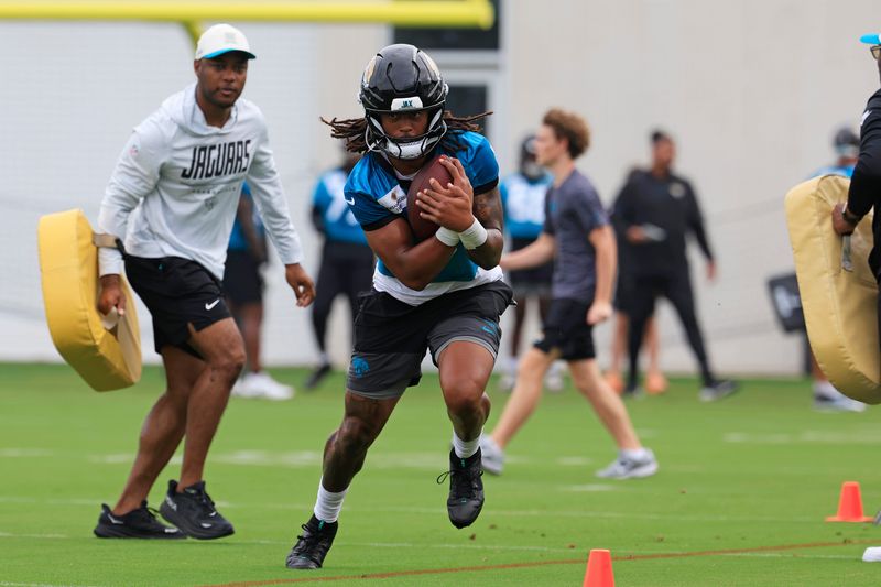 Jacksonville Jaguars wide receiver Jakobi Meyers (3) runs the ball as offensive assistant Fred Walker looks on during the first day of NFL Training Camp at the Miller Electric Center on Wednesday, July 29, 2026, in Jacksonville, Fla.