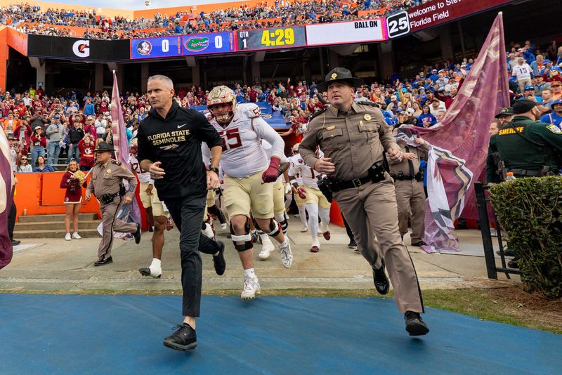 Nov 29, 2025; Gainesville, Florida, USA; Florida State Seminoles head coach Mike Norvell leads his team onto the field before the game against the Florida Gators at Ben Hill Griffin Stadium. Mandatory Credit: Bob Kupbens-Imagn Images