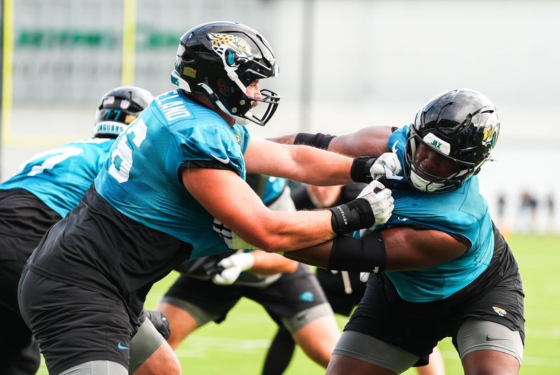 Jaguars lineman Ezra Cleveland (76), left, runs a drill with lineman Jerome Carvin (79) during training camp.