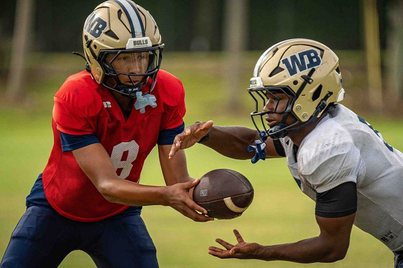 Quarterback Alex Moran (8) makes a handoff to running back Terriel Harmon (5) during varsity football practice for the West Boca Raton Community High School Bulls at the school in unincorporated Palm Beach County, Fla., on Aug 3, 2026. The Bulls are returning from back-to-back Florida High School Athletic Association Class 6A state champions in 2024 and 2025.