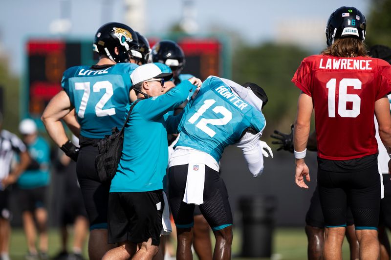 Jacksonville Jaguars equipment manager George Pellicer helps Travis Hunter put a white defensive jersey over his teal offensive jersey during a training camp practice on Aug. 5 at the Miller Electric Center.