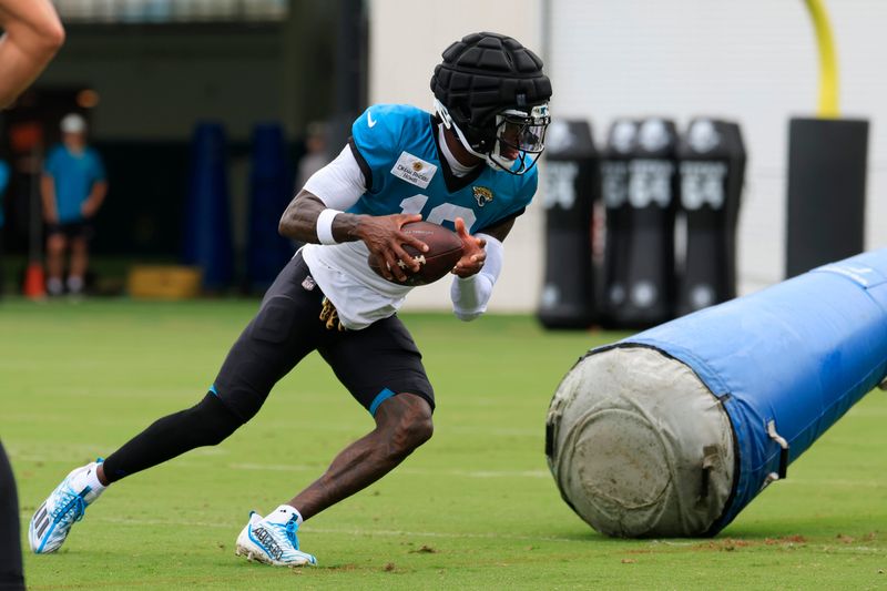 Jacksonville Jaguars wide receiver/cornerback Travis Hunter (12) runs the ball during the sixth day of NFL training camp at the Miller Electric Center on Tuesday, Aug. 4, 2026, in Jacksonville, Fla.