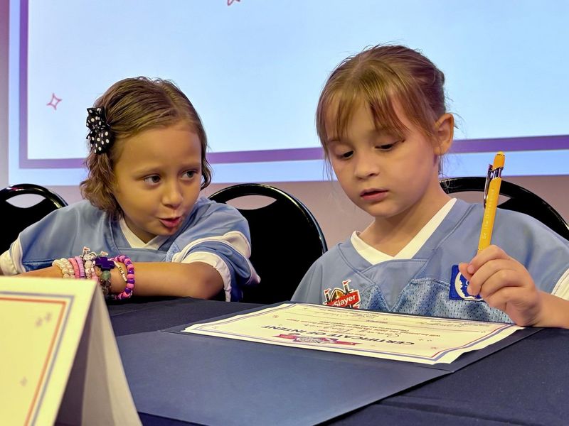 Saige (left) looks on while Sammy signs her TaxSlayer Gator Bowl "Letter of Intent" during a ceremony on Aug. 6 at the WJCT Studios.