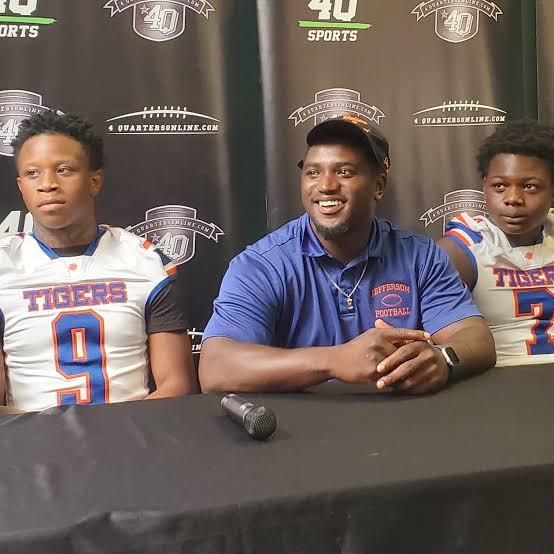 Jefferson County head coach Eric Bright Jr sits with his players Amari Campbell (left), Vinquez Chamber (right) and Jalon Crumity (far right) during high school football media day on Tuesday, July 22, 2025.