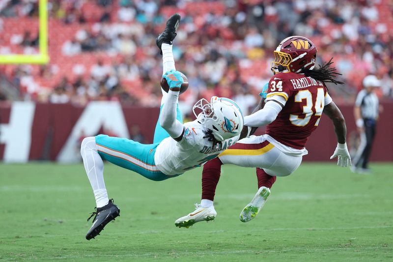 Aug 14, 2026; Landover, Maryland, USA; Miami Dolphins wide receiver Caleb Douglas (7) reaches for a pass as Washington Commanders cornerback Antonio Hamilton Sr. (34) defends during the first half at Northwest Stadium. Mandatory Credit: Amber Searls-Imagn Images