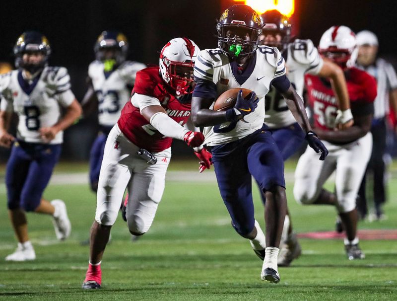 Naples Golden Eagles running back Jevan Raphael (0) runs the ball as Immokalee Indians linebacker Luke McCray (24) tries tackling him during the second quarter of a preseason game at Gary Bates Stadium in Immokalee, Fla., on Friday, Aug. 14, 2026.