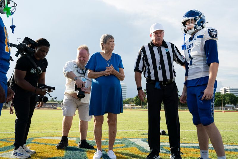 Maurita Budnyk, center, participated in the commemorative coin flip to honor her late husband Sam Budnyk before the Cardinal Newman and  Community School of Naples football game in West Palm Beach, Florida, on August, 21, 2026.