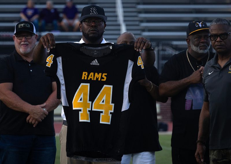 Albert Floyd, Rutherford's head football coach, holds the retired jersey of Alonzo Johnson at Tommy Oliver Stadium in Panama City, Florida, August 21, 2026. Johnson was a 1981 Rutherford High graduate; All-Florida high school football player; Philadelphia Eagles' 1986 second-round draft pick; and University of Florida Athletic Hall of Fame inductee. (Tyler Orsburn/Panama City News Herald)