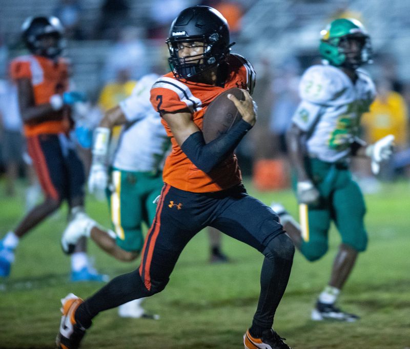 Lake Wales quarterback Kingston Loydd looks behind him as he rushes for a 34-yard touchdown against DeLand in the third quarter on Friday night at Legion Field.