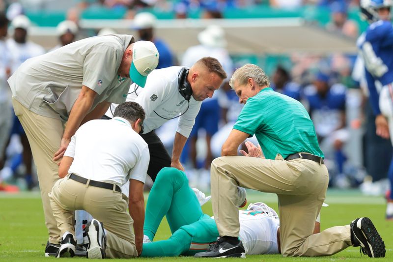 Aug 22, 2026; Miami Gardens, Florida, USA; Miami Dolphins head coach Jeff Hafley checks on linebacker Trey Moore (17) after an apparent leg injury against the New York Giants during the first half at Hard Rock Stadium. Mandatory Credit: Sam Navarro-Imagn Images