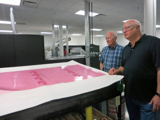 Story City Mayor Mike Jensen and then Councilman Dave Sporleder look at one of the plates being prepared at American Packaging Corporation in March 2017. Ronna Faaborg/Ames Tribune