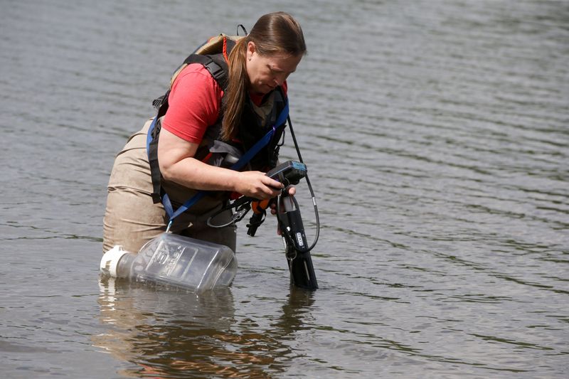 Jacklyn Gautsch, an environmentalist specialist senior with the Iowa Department of Natural Resources, uses a YSI probe to gather data at Backbone Lake such as water temperature, Ph and other measurements Wednesday, July 17, 2024 near Dundee, Iowa.