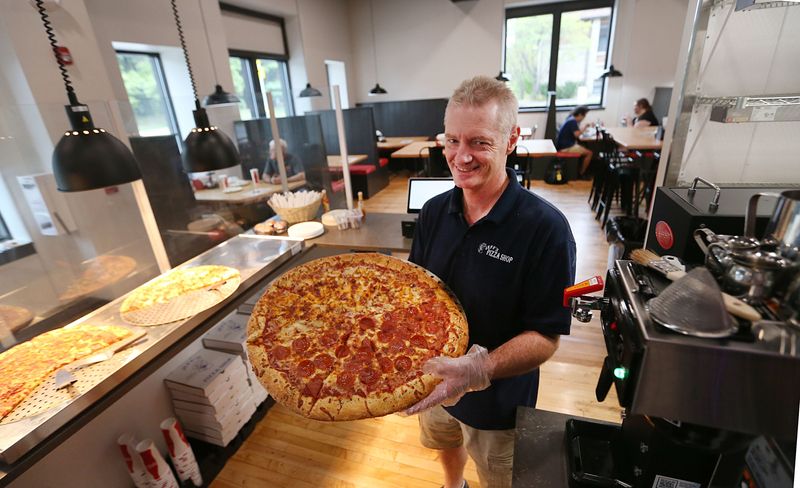 Jeff Uetz, owner of Jeff's Pizza Shop, shows a pizza at the restaurant on Thursday, Sept. 5, 2024, in Ames, Iowa.