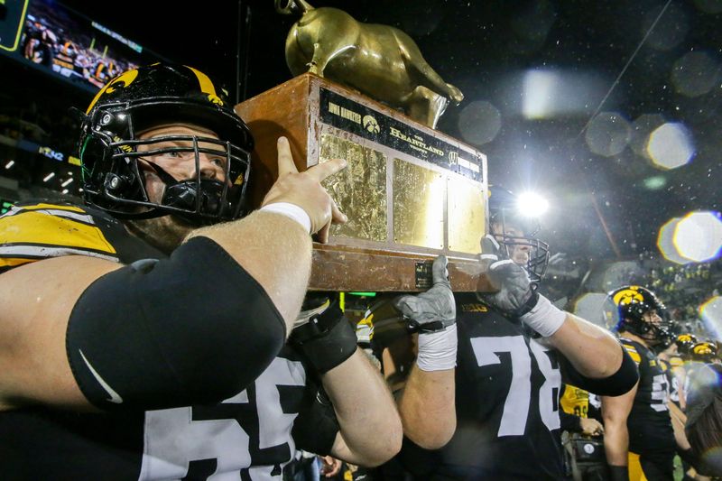 Iowa offensive linemen Logan Jones (65) and Mason Richman (78) carry The Heartland Trophy off the field after defeating Wisconsin Saturday, Nov. 2, 2024 at Kinnick Stadium in Iowa City, Iowa.