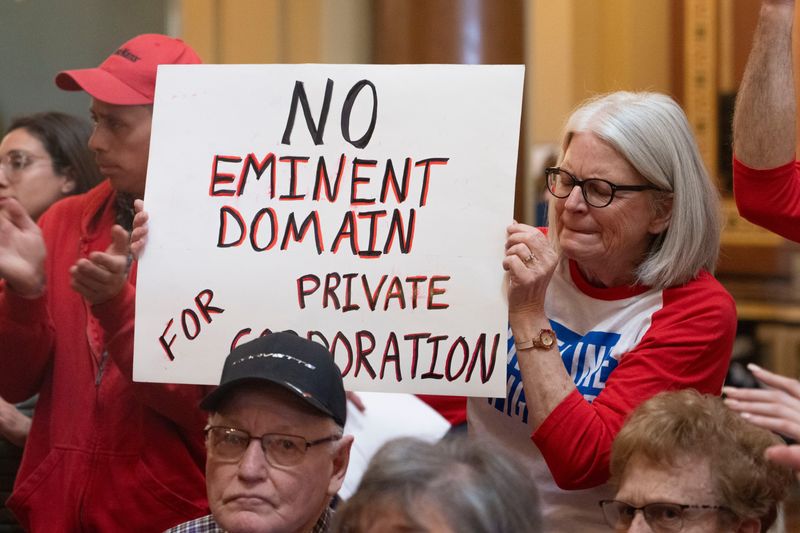 People hold signs as pipeline opponents speak during a rally against eminent domain for carbon capture pipelines on Tuesday, March 18, 2025, in Des Moines.