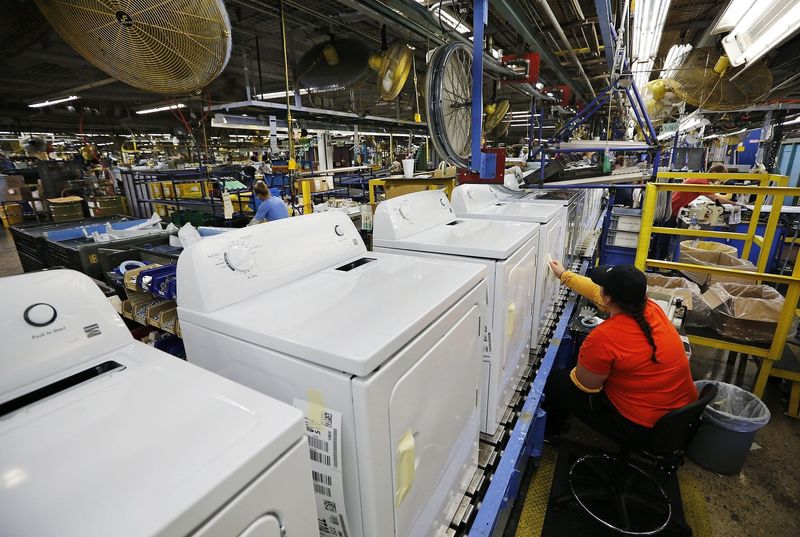 An employee inspects dryer doors at a Whirlpool plant.