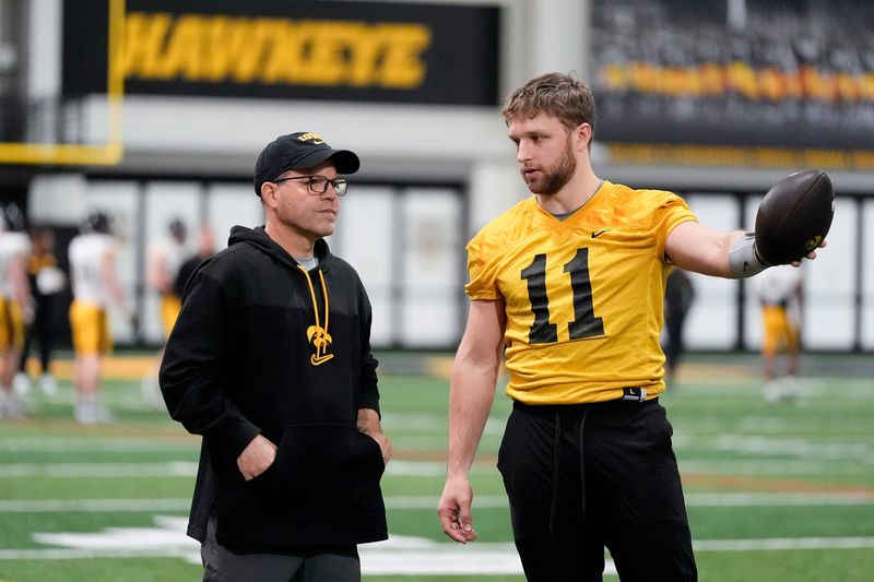 Iowa's senior football analyst Warren Ruggiero, left, talks to quarterback Mark Gronowski (11) during practice on April 3 in Iowa City.