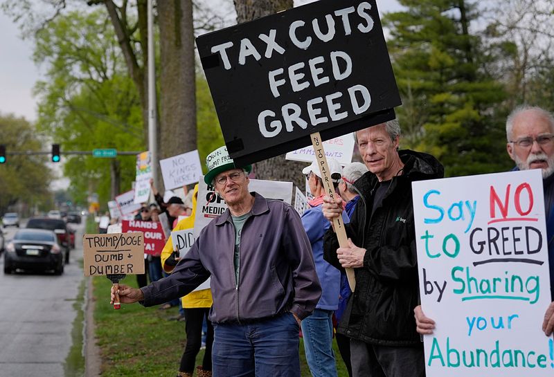 Protesters hold signs during a May Day rally along Duff Avenue on May 1, 2025, in Ames, Iowa.