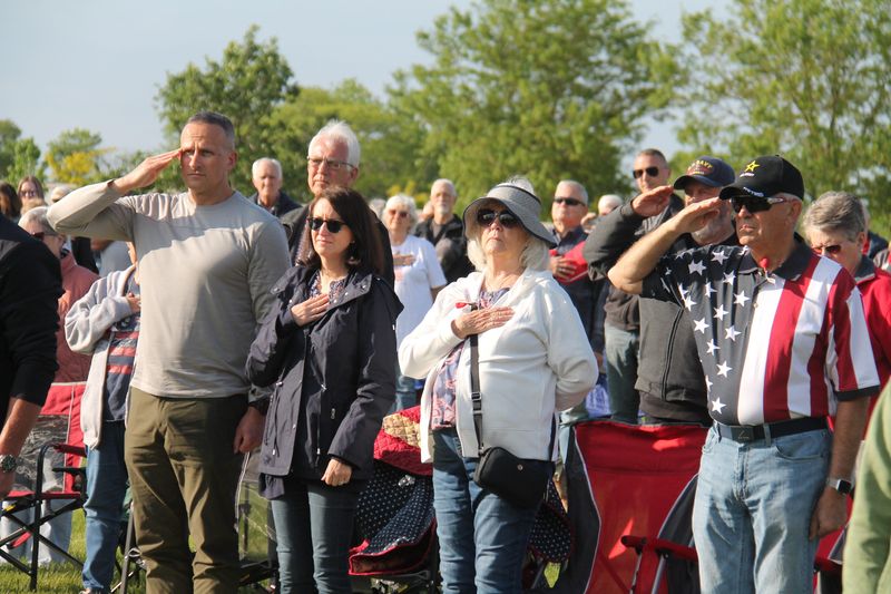 Attendees honor the flag as the national anthem is sung during a Memorial Day ceremony on Monday, May 26, 2025, at Iowa Veterans Cemetery.