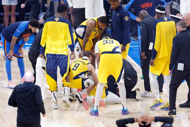 Indiana Pacers guard Tyrese Haliburton (0) is assisted by teammates and staffers after injuring his Achilles tendon against the Oklahoma City Thunder during Game 7 of the NBA Finals.