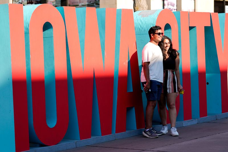 People pose with an Iowa City sign during the Downtown Iowa City Block Party June 28, 2025 in Iowa City, Iowa.