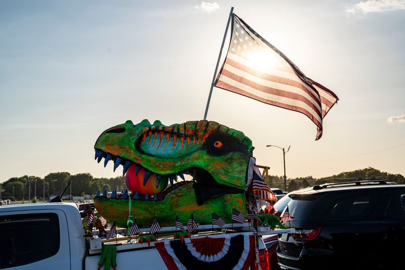 The sun shines through a flag on the back of a car titled the “Patriosaurus” during the American 250 kickoff event on July 3, 2025, at the Iowa State Fairgrounds in Des Moines.