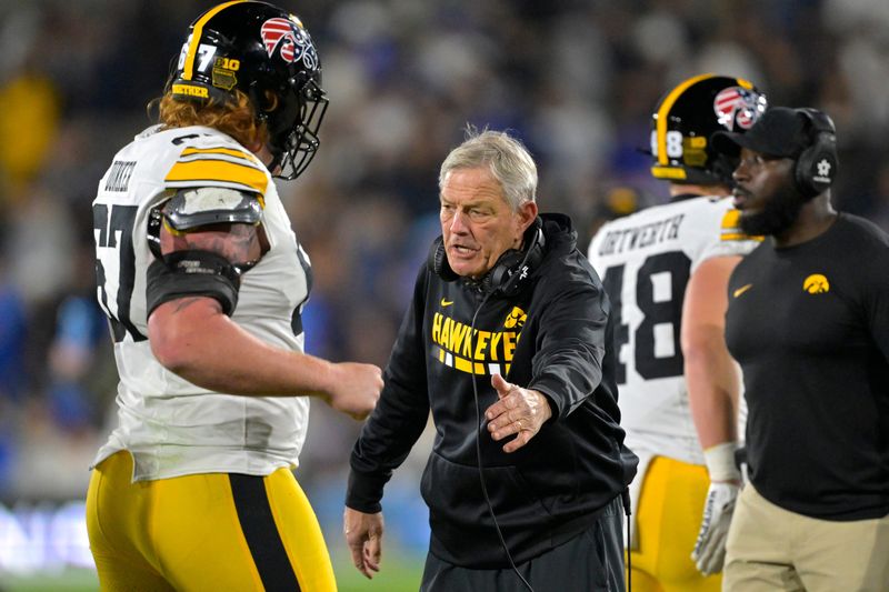 Nov 8, 2024; Pasadena, California, USA; Iowa Hawkeyes head coach Kirk Ferentz shakes hands with Iowa Hawkeyes offensive lineman Gennings Dunker (67) after a score in the second half against the UCLA Bruins at the Rose Bowl. Mandatory Credit: Jayne Kamin-Oncea-Imagn Images