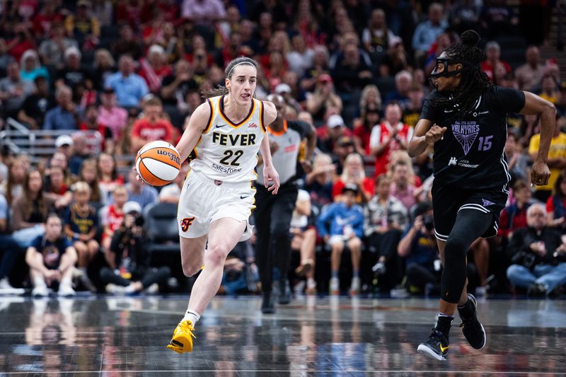 Jul 9, 2025; Indianapolis, Indiana, USA; Indiana Fever guard Caitlin Clark (22) dribbles the ball while Golden State Valkyries guard Tiffany Hayes (15) defends in the first half at Gainbridge Fieldhouse. Mandatory Credit: Trevor Ruszkowski-Imagn Images