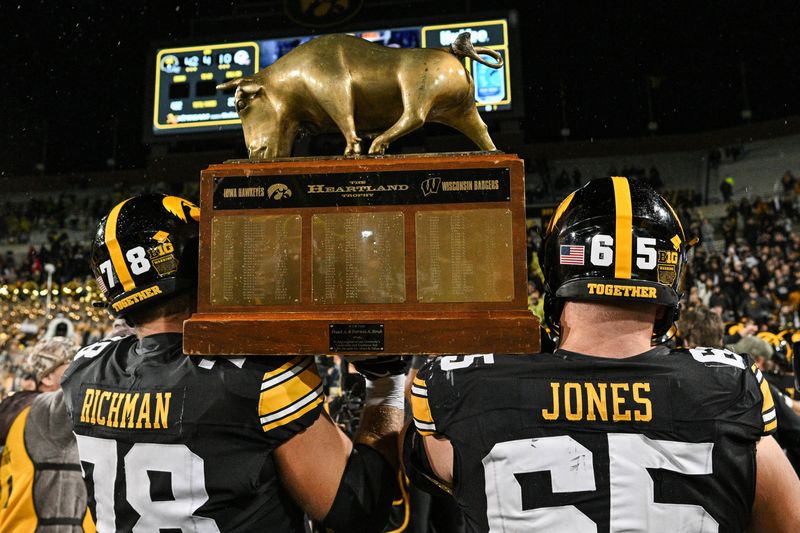 Nov 2, 2024; Iowa City, Iowa, USA; Iowa Hawkeyes offensive lineman Logan Jones (65) and offensive lineman Mason Richman (78) carry the Heartland trophy after the game against the Wisconsin Badgers at Kinnick Stadium. Mandatory Credit: Jeffrey Becker-Imagn Images