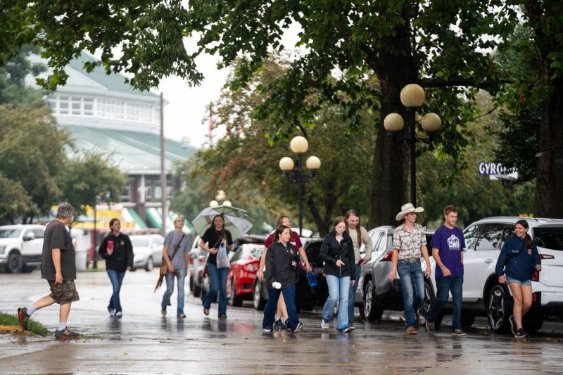 A group walks through the rain as the fairgrounds prepare for the 2025 Iowa State Fair on Aug. 6, 2025, in Des Moines.
