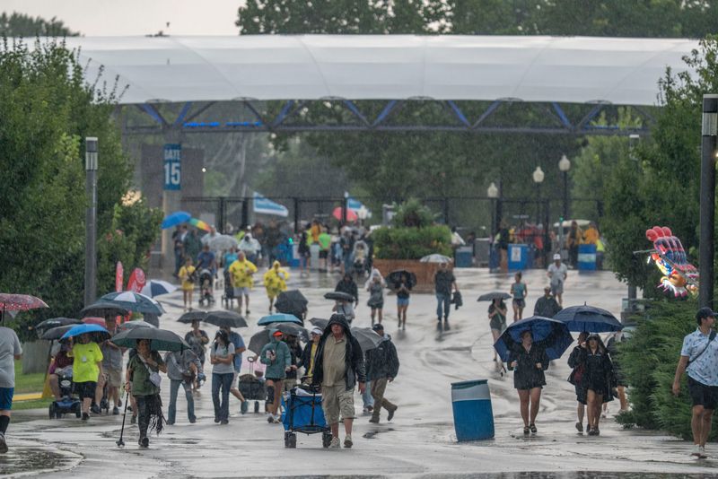 Fairgoers enter near gate 15 as rain falls during the first day of the Iowa State Fair on Aug. 7, 2025, in Des Moines.