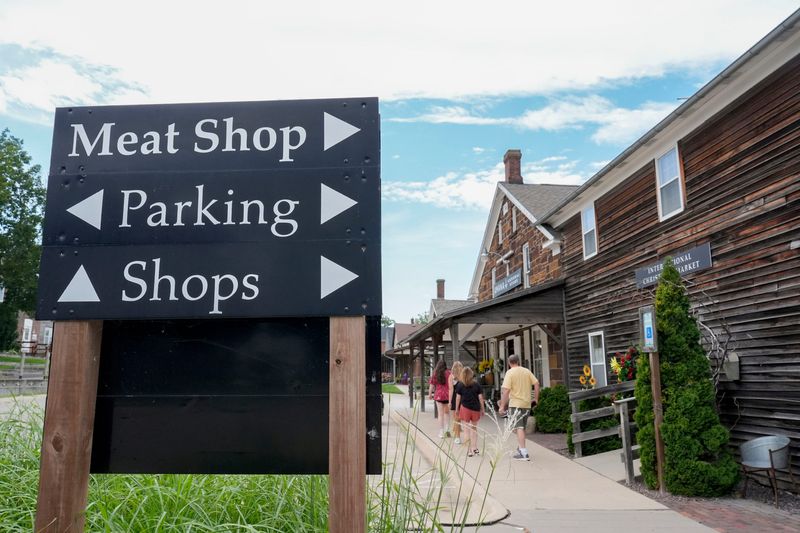 People wander past shops and signs Aug. 6, 2025, at the Amana Colonies in Iowa.