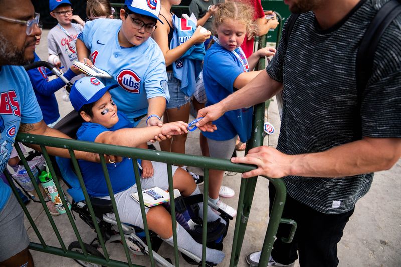 Ryker Colon hands a blue ‘Team Ryker’ bracelet to Cubs pitcher Cade Horton on Aug. 17, 2025, outside Wrigley Field in Chicago, Illinois.