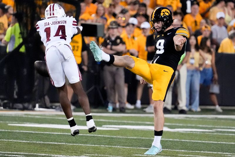 Massachusetts wide receiver Kezion Dia-Johnson (14) blocks a punt by Iowa's Rhys Dakin on Sept. 13, 2025 at Kinnick Stadium in Iowa City.
