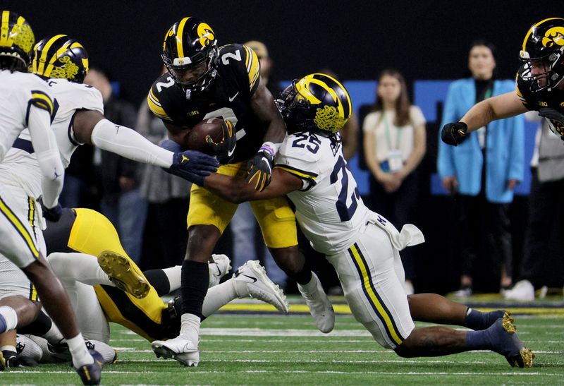 Dec 2, 2023; Indianapolis, IN, USA; Michigan Wolverines linebacker Junior Colson (25) tackles Iowa Hawkeyes running back Kaleb Johnson (2) during the first half of the Big Ten Championship game at Lucas Oil Stadium. Mandatory Credit: Trevor Ruszkowski-USA TODAY Sports