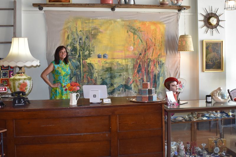 Laurie Delebreau, owner of Uncommon Digs vintage store in Jewell, poses in front of an abstract mural painted by her friend Becky Kafka of Wisconsin.