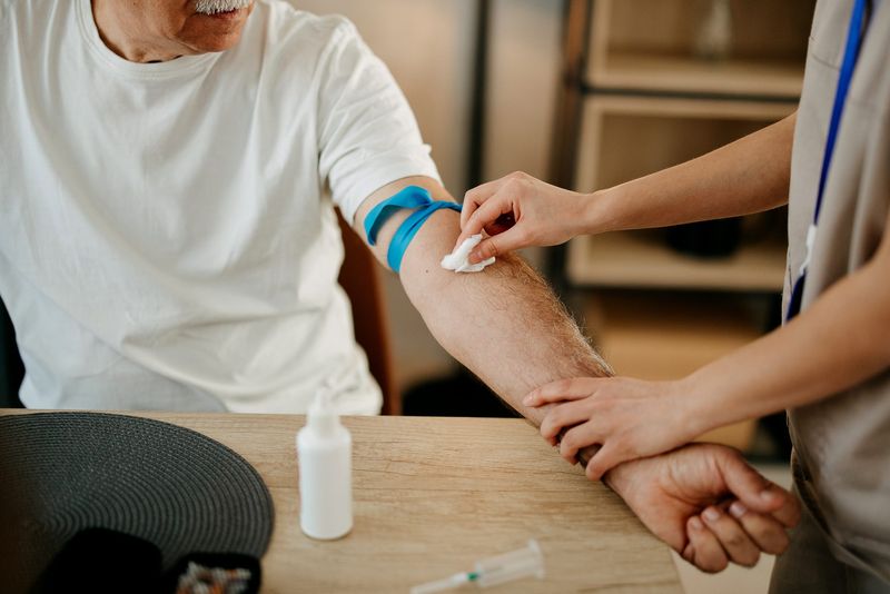 Nurse drawing blood from an elderly man in his home