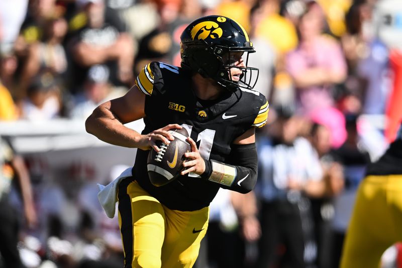 Sep 27, 2025; Iowa City, Iowa, USA; Iowa Hawkeyes quarterback Mark Gronowski (11) rolls out to throw a pass against the Indiana Hoosiers during the first quarter at Kinnick Stadium. Mandatory Credit: Jeffrey Becker-Imagn Images