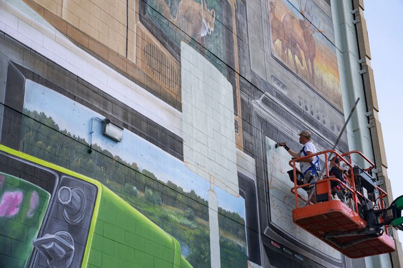 Artists Leon Keer, left, and Massina, right, work on a new mural at 901 Grand Avenue on Wednesday, Oct. 8, 2025, in Des Moines.