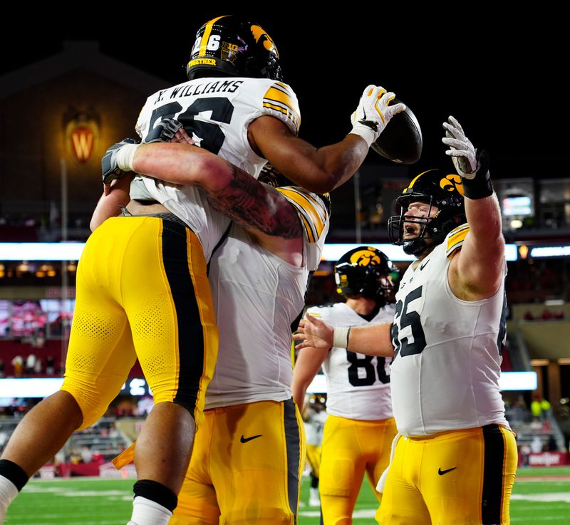Iowa Hawkeyes offensive lineman Gennings Dunker (67) lifts running back Xavier Williams (26), celebrating the touchdown during the second half of the game against the Wisconsin Badgers on Saturday October 11, 2025 at Camp Randall in Madison, Wisconsin.