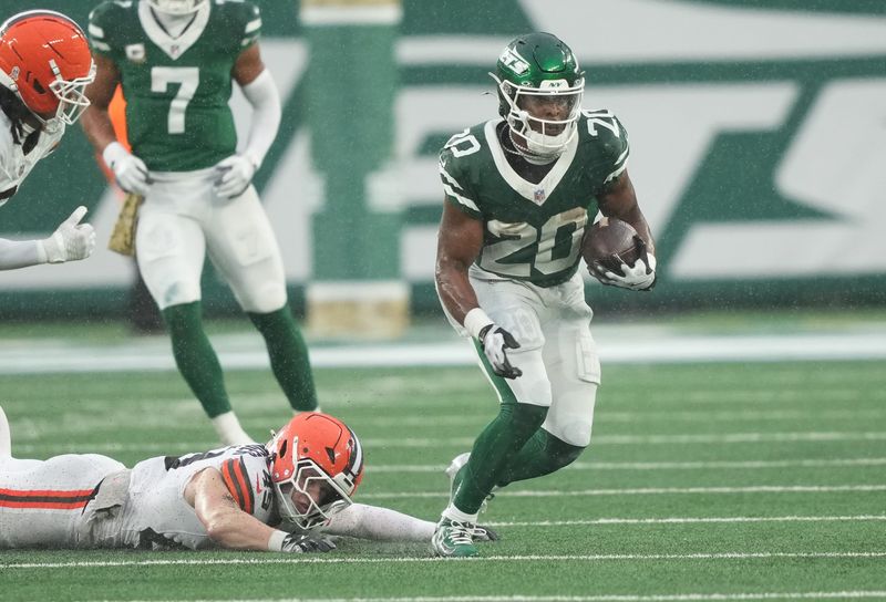 Nov 9, 2025; East Rutherford, New Jersey, USA; New York Jets running back Breece Hall (20) runs past Cleveland Browns linebacker Carson Schwesinger (49) during the second half at MetLife Stadium.