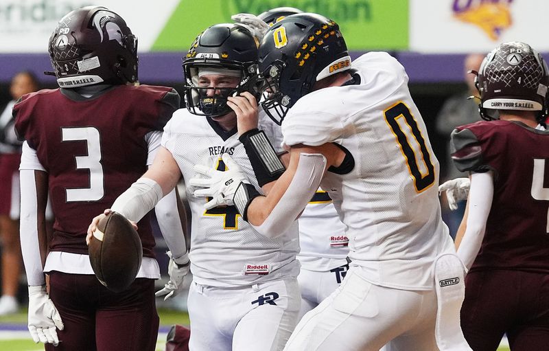 Regina Catholic quarterback Kyle Tracy (4) celebrates with Tate Wallace (0) after scoring a touchdown against Grundy Center during the second quarter of the Regals' 31-12 victory over the Spartans in the Class 1A high school football state semifinals on Nov. 14, 2025, at UNI-Dome in Cedar Falls, Iowa.