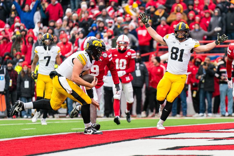 Nov 28, 2025; Lincoln, Nebraska, USA; Iowa Hawkeyes quarterback Mark Gronowski (11) scores a touchdown as tight end DJ Vonnahme (81) celebrates during the fourth quarter against the Nebraska Cornhuskers at Memorial Stadium. Mandatory Credit: Dylan Widger-Imagn Images