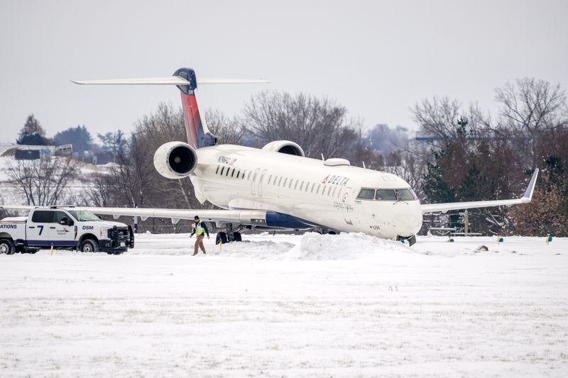 Des Moines International Airport staff checks over a Delta flight that slid off the end of the runway Saturday night. The airport is expected to be closed until mid-morning Sunday, Nov. 30, 2025.