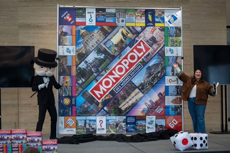 Sarah Bowman, of Top Trumps USA, right, and Mr. Monopoly, unveil the Des Moines Monopoly board during the announcement for the Des Moines Monopoly board at Ruan Center on Tuesday, Dec. 9, 2025, in Des Moines.