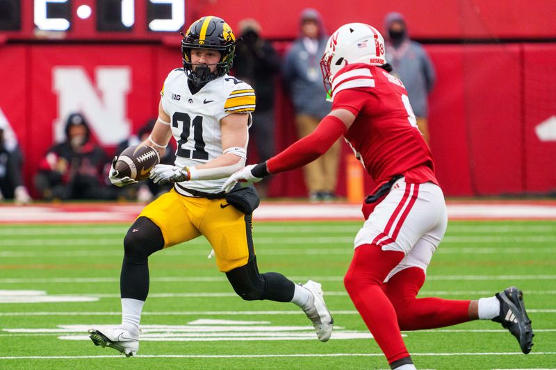 Nov 28, 2025; Lincoln, Nebraska, USA; Iowa Hawkeyes wide receiver Kaden Wetjen (21) runs against Nebraska Cornhuskers defensive back Deshon Singleton (8) during the third quarter at Memorial Stadium. Mandatory Credit: Dylan Widger-Imagn Images