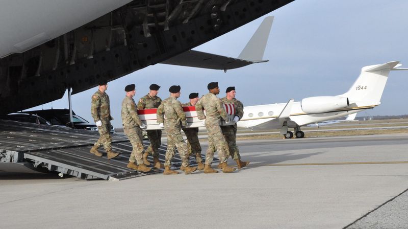 Military personnel carry a transfer case draped with an American flag from a plane to a van during the dignified transfer at Dover Air Force Base on Dec. 17, 2025 for two National Guard soldiers and a civilian interpreter killed in Syria.